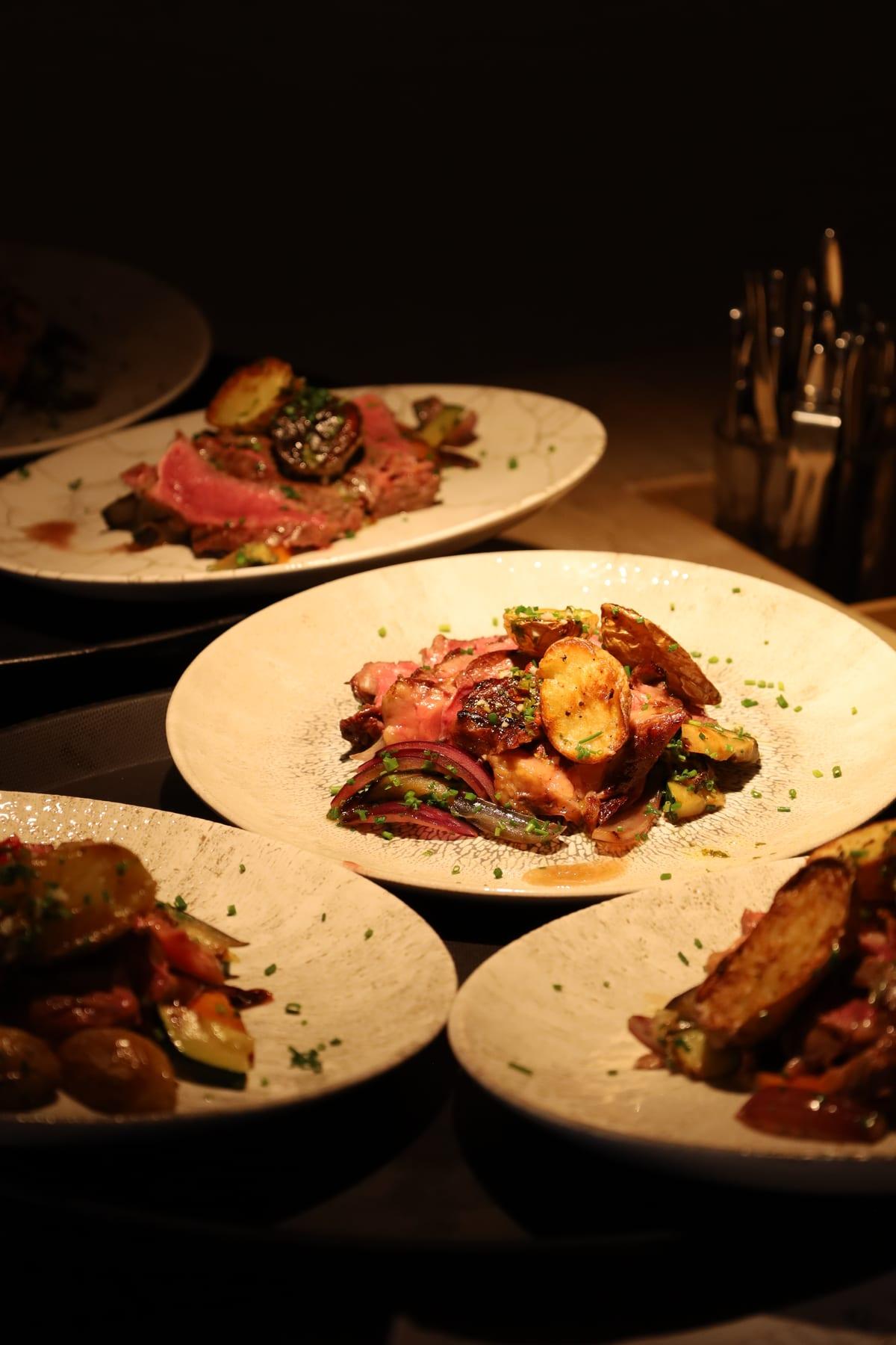Plated dishes with meat, potato and vegetables at a restaurant