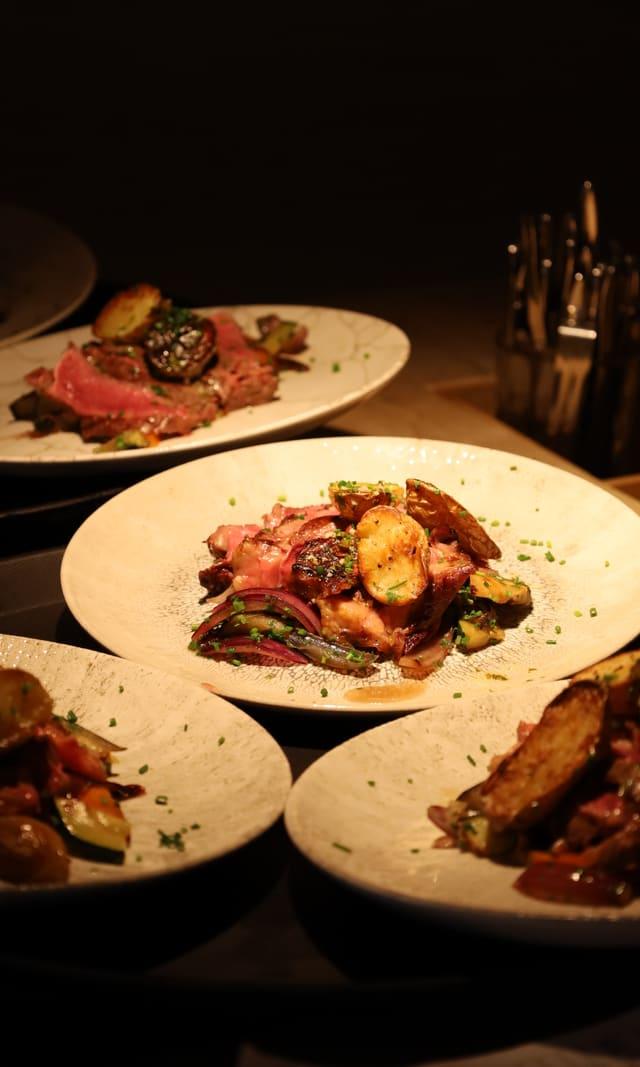 Plates of meat and roast vegetables on a dimly lit table