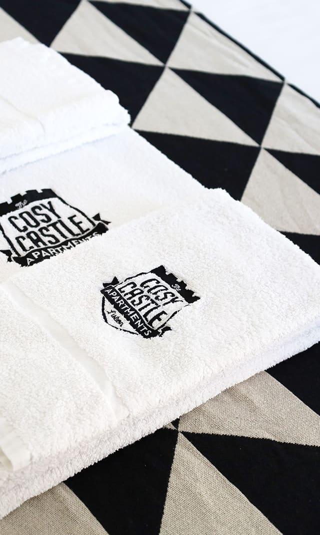 Embroidered Cosy Castle towels folded on the bed