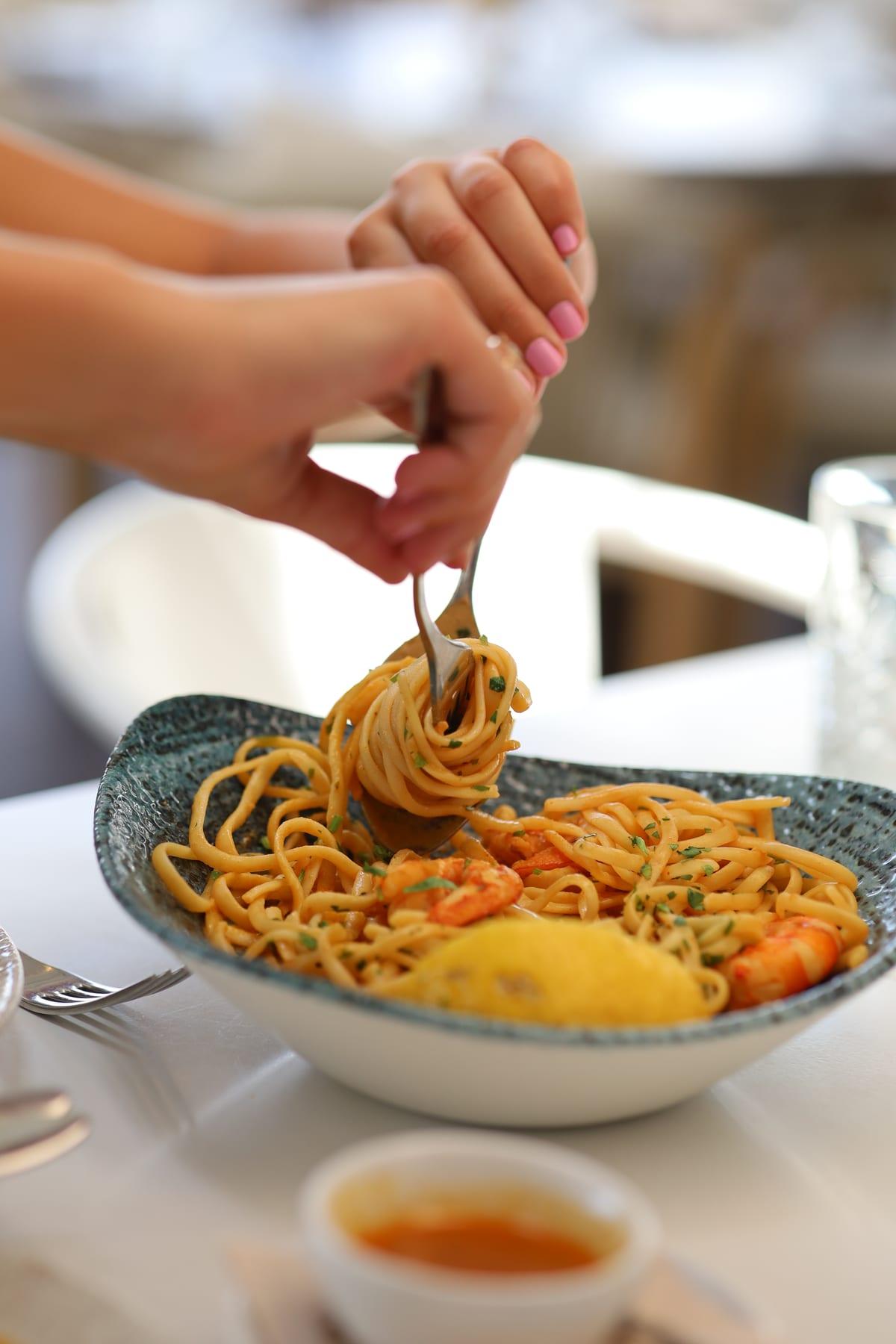 Fork twirling pasta with prawns on a restaurant plate